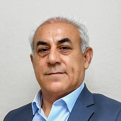 Dr. Majid Rezaei wearing a dark suit jacket over a light blue collared shirt